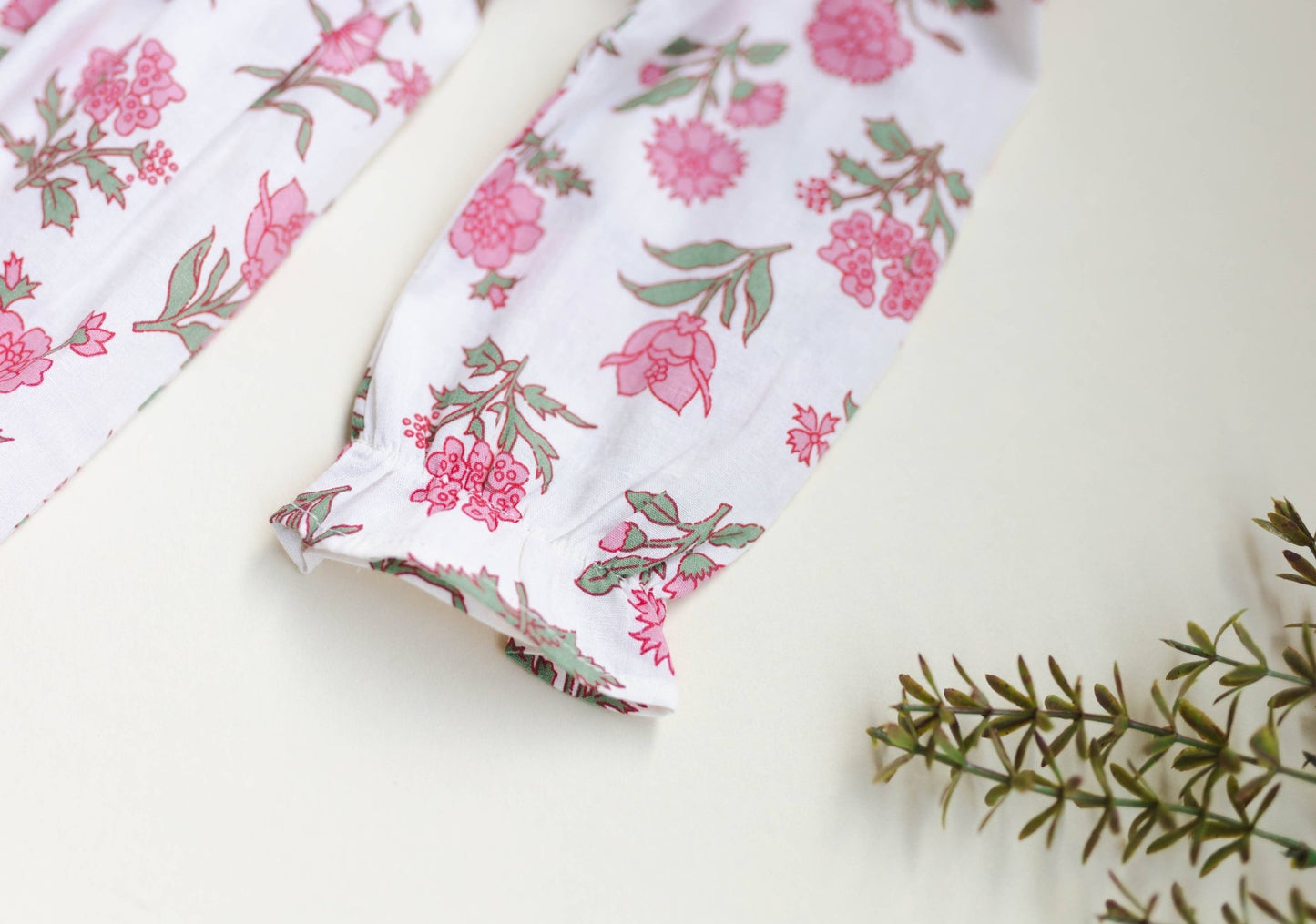 Close-up of the artisan pink block print floral pattern on soft off-white 100% cotton fabric.
