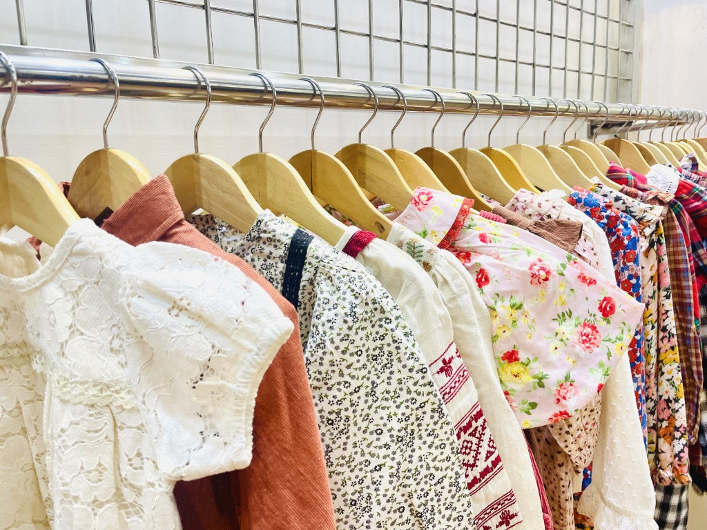 LARILI Children's clothing on hangers against a tiled wall