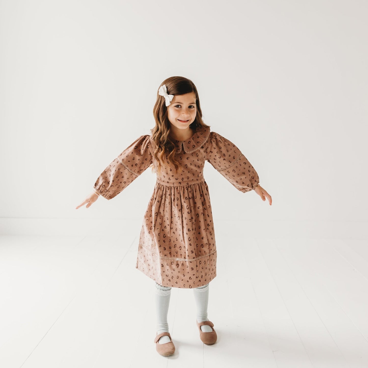 5-year-old girl posing in LARILI Cord Crush dress. Lavender animal print corduroy with lace collar and handmade details.