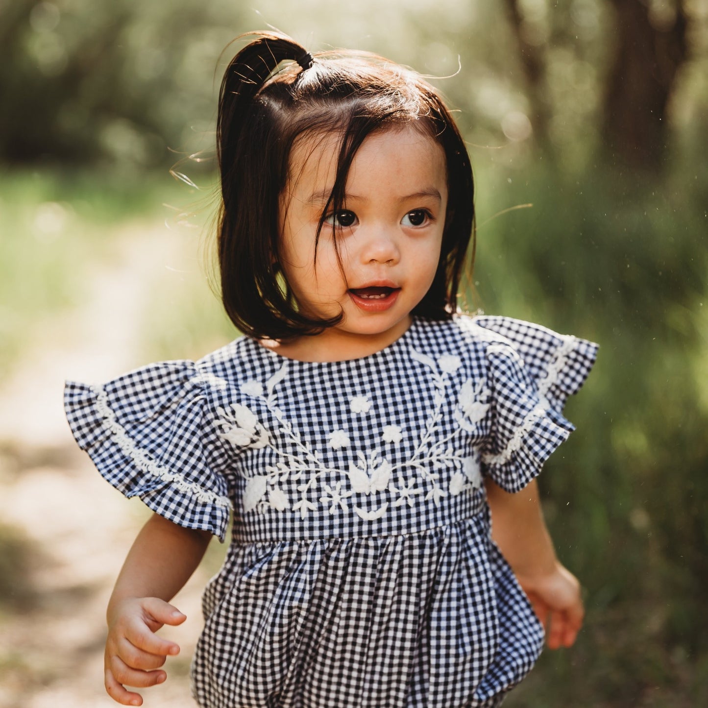 A 2-year-old model showing the close up of Embroidered Yoke Eith Ruffle Sleeves Romper - LARILI