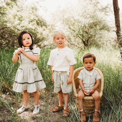 Little girl group photo wearing LARILI green gingham pinafore with embroidered white blouse. 100% cotton outfit for siblings.