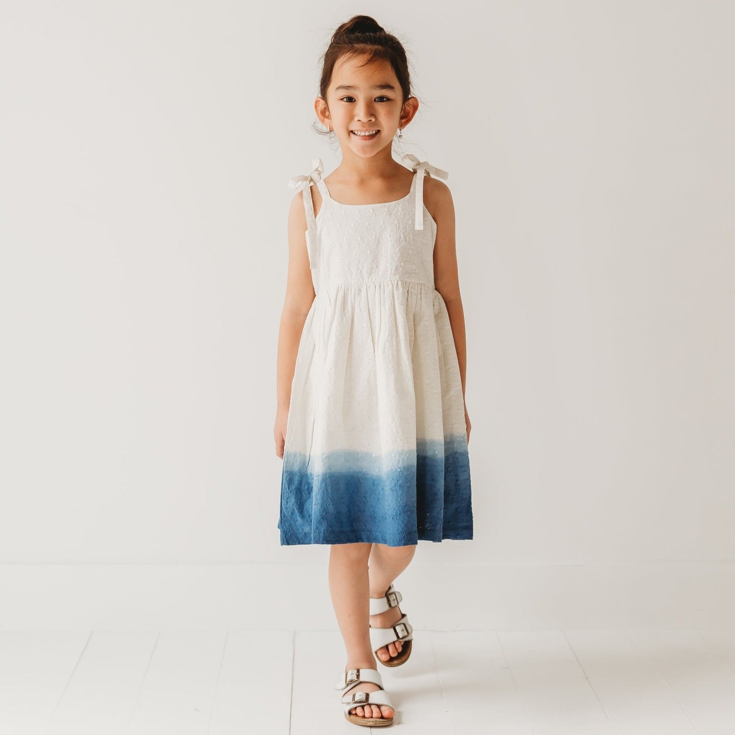 5-year-old girl in LARILI ocean ombre dress. Blue gradient 100% cotton Schiffli fabric with nautical embroidery.