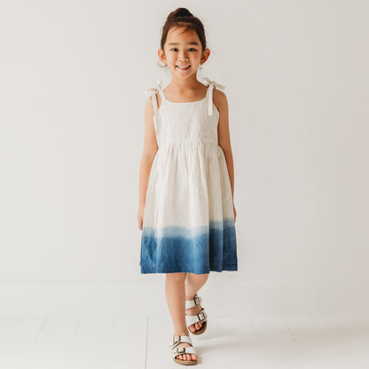 5-year-old girl in LARILI ocean ombre dress. Blue gradient 100% cotton Schiffli fabric with nautical embroidery.