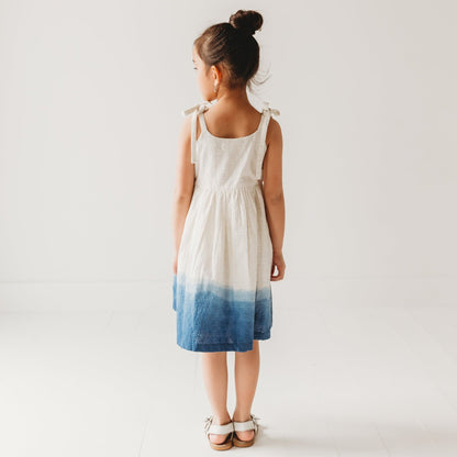 back view of 5-year-old girl in LARILI ocean ombre dress. Blue gradient 100% cotton Schiffli fabric with nautical embroidery.