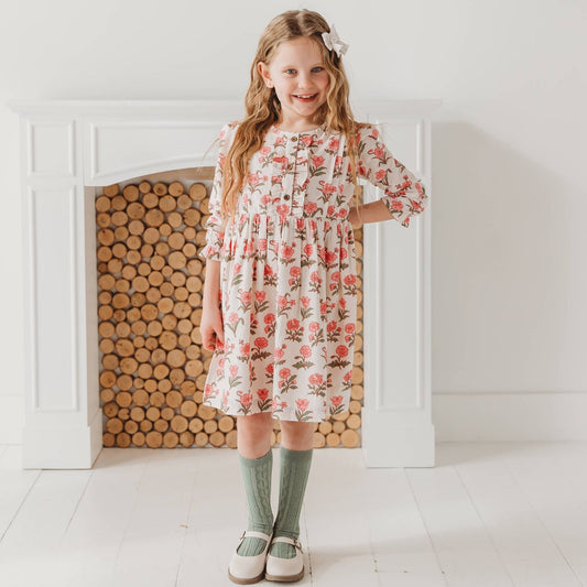 Young girl posing in the Pink Block Print Flower cotton dress. Elegant off-white and pink festive holiday fashion by LARILI.