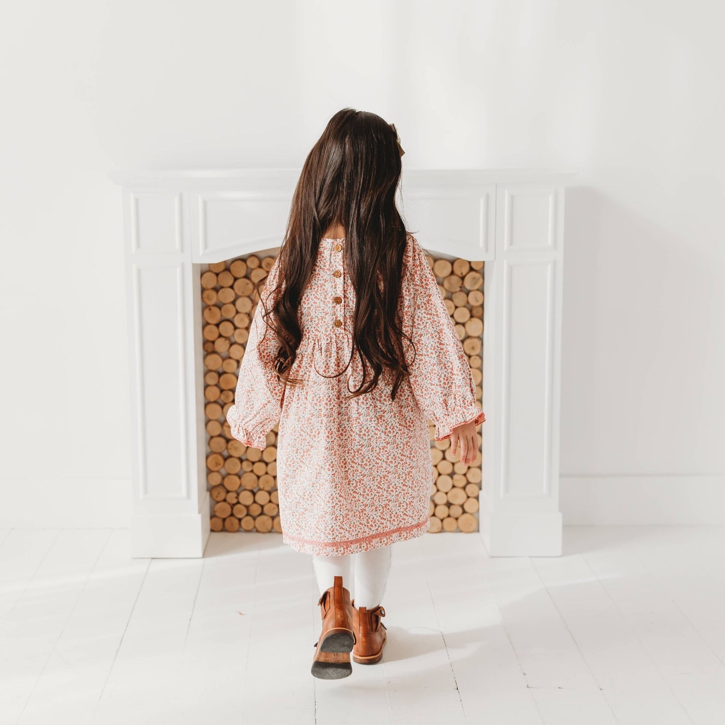 Back view of little girl twirling in a LARILI pink ditsy floral corduroy dress with lace details. Soft autumn vintage-style girls' clothing.