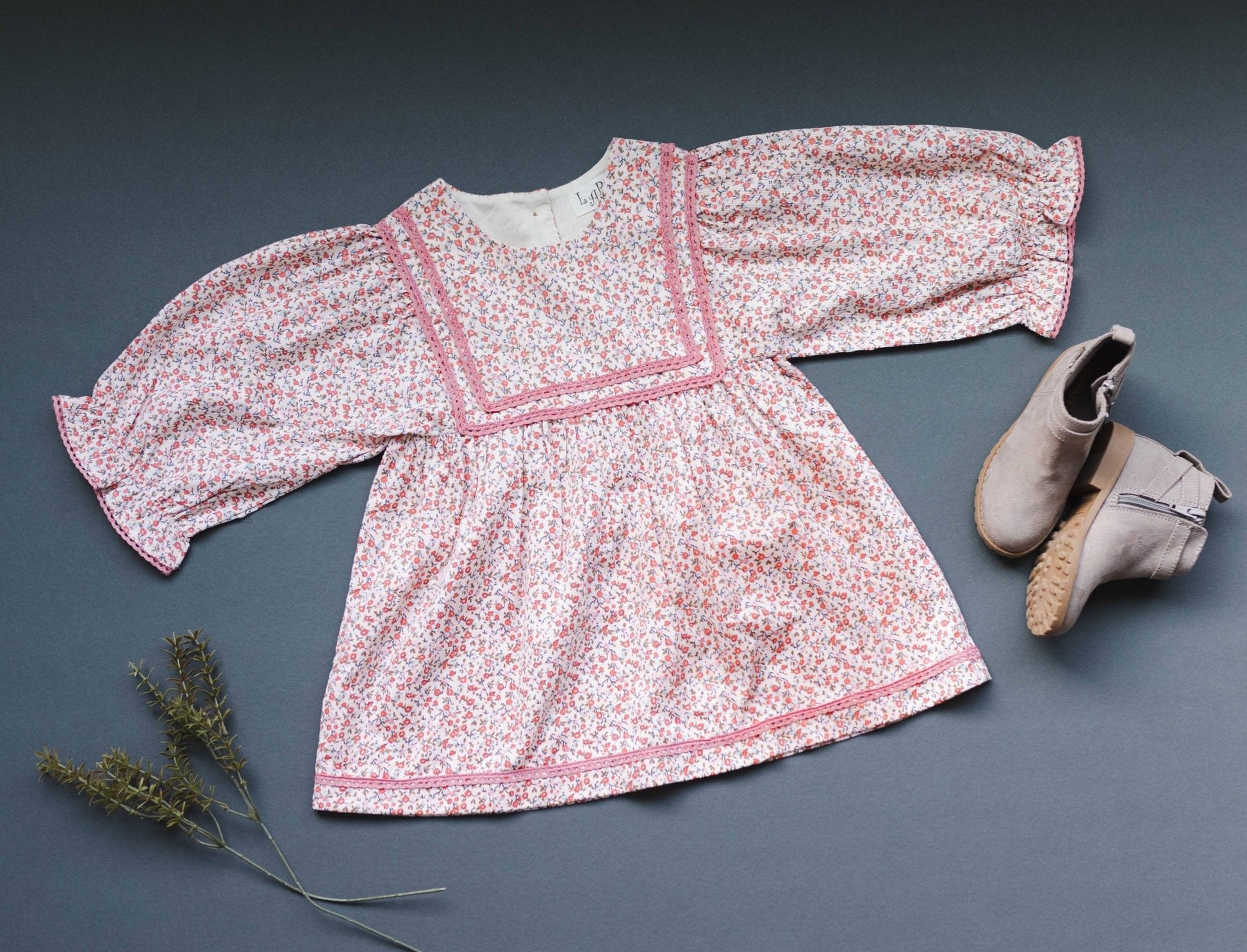 Overhead view of the LARILI pink ditsy print corduroy dress, highlighting the soft fabric texture, floral patterns, and lace detailing.