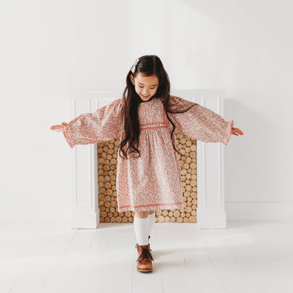 Little girl twirling in a LARILI pink ditsy floral corduroy dress with lace details. Soft autumn vintage-style girls' clothing.