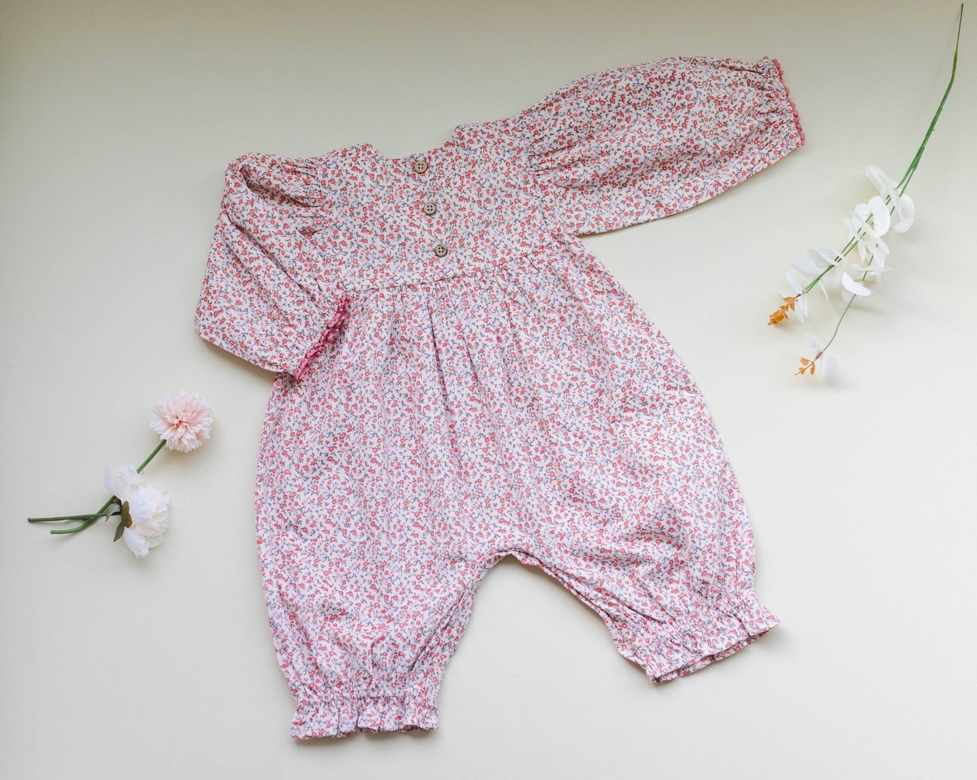 Back view of soft pink corduroy romper, showing ditsy print and delicate lace. Vintage-style baby fashion